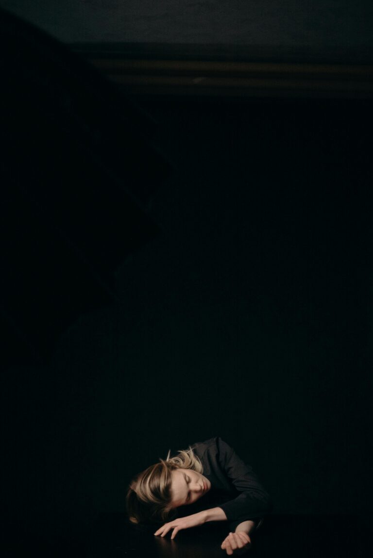 A serene portrait of a woman asleep against a dark background, conveying relaxation and calm.
